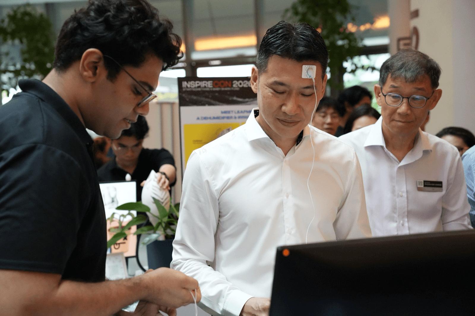 Mr David Neo, former Chief of Army, wearing Neural Drive's forehead electrode and earphones as he tries the device at INSPIRECON 2025